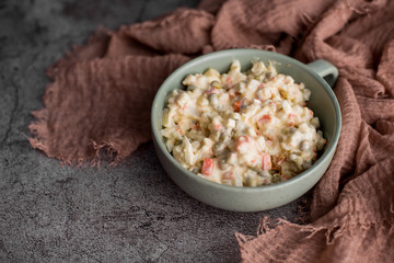 Bowl of traditional Russian salad called Olivie, Russian New Year or Christmas salad on wooden background. Salad from cooked vegetables. Potato salad.