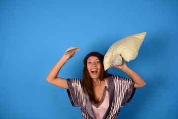 joyful woman woke up holding a pillow white saucer on a blue background