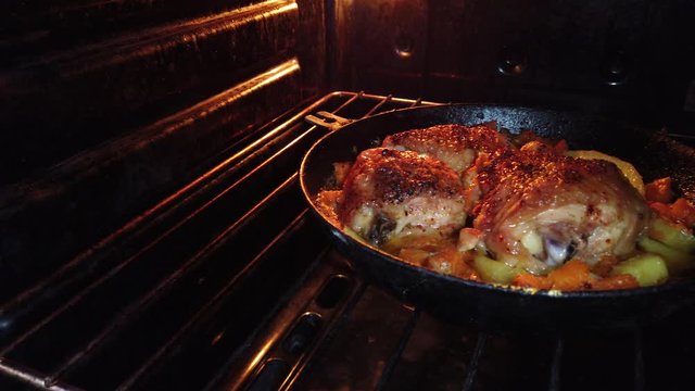 cooking meat in a pan. Fried chicken with vegetables in a pan in the oven