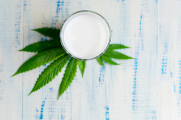 Milk from hemp in a cup on a sheet of hemp on a wooden background.