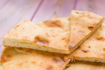 Pie with cheese on a wooden pink background. Khachapuri - flat cake with cheese.