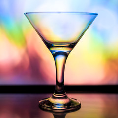 A martini glass on the bright rainbow coloured background.
