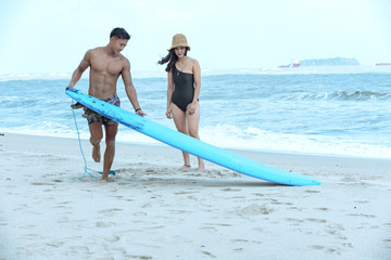 Asian surfer teacher man teach practice woman student during private surf class lesson.