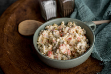 Bowl of traditional Russian salad called Olivie, Russian New Year or Christmas salad on wooden background. Salad from cooked vegetables. Potato salad.