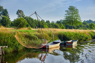 Image of La Vilaine River, Brittany, France with fishing boats, nets, trees and reflections.