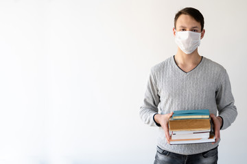 learning during coronavirus, a young guy on a white background. Books and textbooks in the hands.