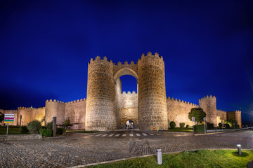 Avila, Spain. View of historic city gate Puerta de San Vicente at dusk