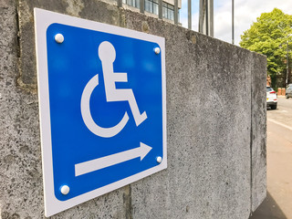 Close up view of a sign showing the way to an access ramp for disabled persons.