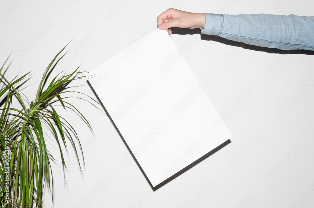 Wall mural A3 Poster Mock-Up - Man in a denim shirt holding a poster on a white background. Hipster Aesthetic