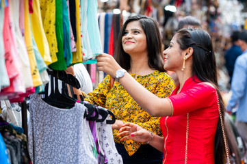 Two Beautiful brunette Indian girls looking for new clothes in market for festival season