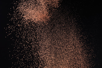 flying particles and cocoa powder on a black background, frozen topping for dessert