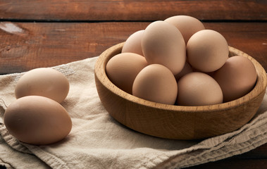 raw brown chicken eggs in a wooden plate on the table