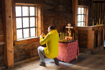 Young man taking photo in a wooden church, Kizhi, Russia