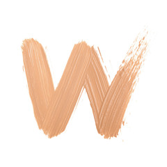 Letter W made with face skin concealer nude color.  Brush stroke make up base creamy texture isolated on white background.