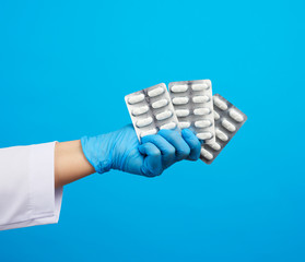 female hand with blue sterile gloves holds a pills in a blister, concept for drug treatment of...