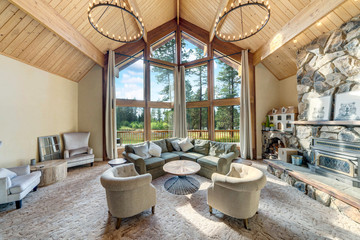 Grant huge living room with grant fireplace and three sotry tall windows in an amazing luxury room with open staricase and wooden vaulted ceiling.