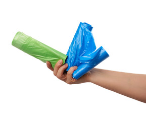 female hand holds a bundle of green and blue plastic bags for garbage