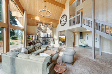 Grant huge living room with grant fireplace and three sotry tall windows in an amazing luxury room with open staricase and wooden vaulted ceiling.