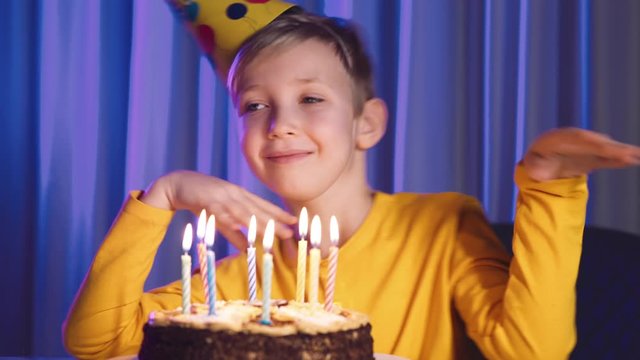 Boy celebrates his birthday.  Cute boy blows out candles on a cake on his birthday.  Happy child looks at a cake with candles. Child looks at the cake and makes a birthday wish. Happiness concept
