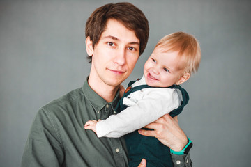 a one-year-old son sits in the arms of a young father