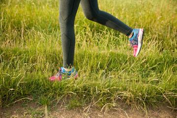 Beautiful young woman workout outdoor runs across meadow in early summer