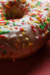 
Two juicy fresh sweet donuts with sugar icing and sprinkles on a pink background