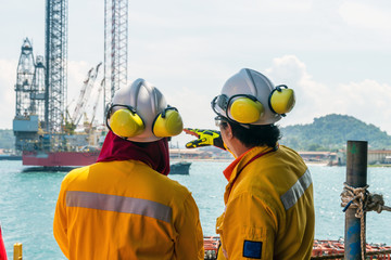 A construction supervisor giving a briefing to fellow workers during mobilization of a work barge at a port