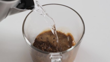 Making instant black coffee in glass cup. Pour hot water. Slow motion.