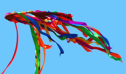 Wooden wheel with bright ribbons isolated on blue sky background. Сelebration of Midsummer, carnival, Pancake week