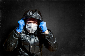 a man in a medical mask and gloves pulled his hood up