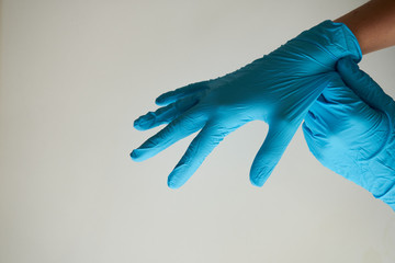 Woman hands remove a wearing blue disposable latex glove, taking off a rubber glove for professional medical safety and hygiene protection from Coronavirus disease COVID-19 and surgery and medical