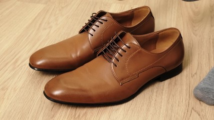 Man to wear his elegant brown shoes. Close up.