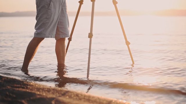 A Young Man's Leg Standing On The Shoreline While Taking Video Of A Sunset In Lake Bracciano, Italy - Medium Shot