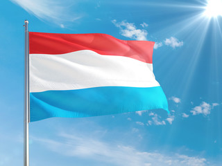 Luxembourg national flag waving in the wind against deep blue sky. High quality fabric. International relations concept.