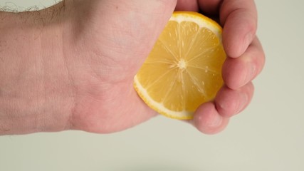 Female hand squeezing juice from fresh lemon. Close up.