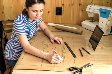 the girl sews clothes at home, works remotely, builds a pattern, seamstress