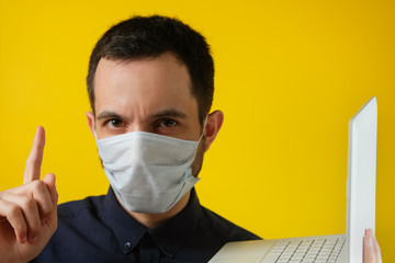 Man in a medical mask with a laptop focuses on statistics.