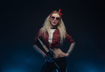 Fototapeta na wymiar a bright blonde in a red hat with a submachine gun on a dark background