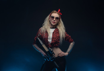 a bright blonde in a red hat with a submachine gun on a dark background