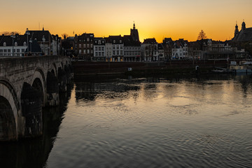 Naklejka premium Sunset in early April with a view on the river Meuse, the old roman Sint Servaas bridge and the skyline of Maastricht