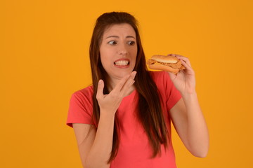 woman in pink t-shirt looks at a burger on a yellow background fast food