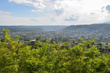 Fototapeta premium Panoramic rural landscape small houses on a hill near the ancient French village Saint-Paul-de-Vence with the Maritime Alps mountains in the distance, Provence, France at sunny summer day