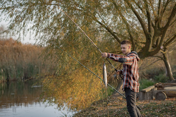 Fototapeta premium Man by the river. Guy in a red shirt. Man in a fishing.