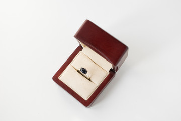 White golden ring with blue sapphire in wood box. Isolated on grey background.