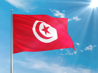 Tunisia national flag waving in the wind against deep blue sky. High quality fabric. International relations concept.
