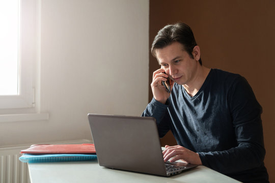 Man using laptop and smartphone at home office