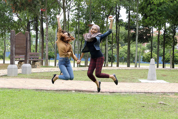Obraz premium Young Asian Malay man woman outdoor green park joy happy jump in the air