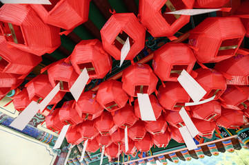 Traditional red lantern with white paper hanging on ceiling of temple