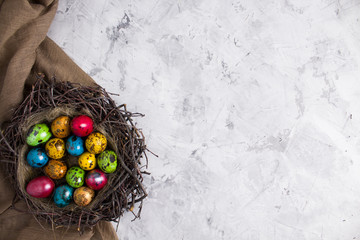 Quail eggs for the easter holiday. Colorful eggs in a nest on a light background. Copy space, top view