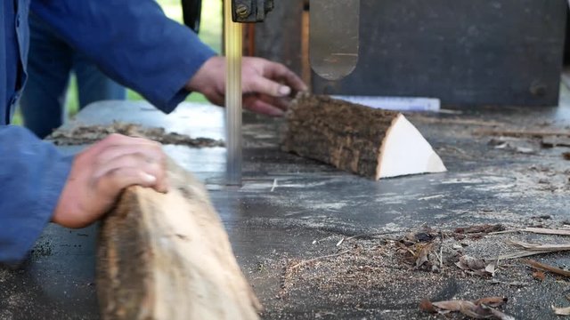 Brennholz oder Holzscheite s&auml;gen mit einer Bands&auml;ge